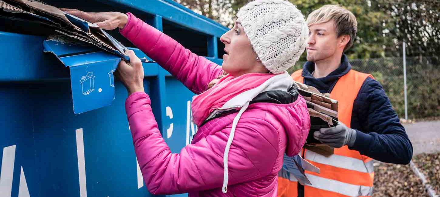 Eine Frau legt Karton in den Kartonbehälter