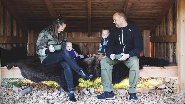 Mutter, Vater und zwei kleine Kinder entspannen sich auf einem Bisonversteck in einem großen Unterstand