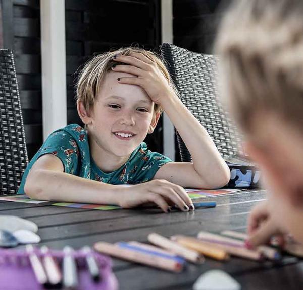 Dreng smiler til sin søster ved bordet i sommerhuset