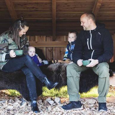 Mutter, Vater und zwei kleine Kinder entspannen sich auf einem Bisonversteck in einem großen Unterstand