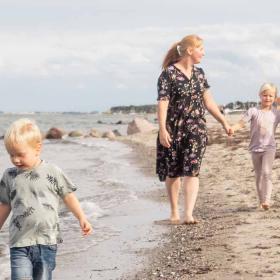 Familie med tre børn går tur på stranden