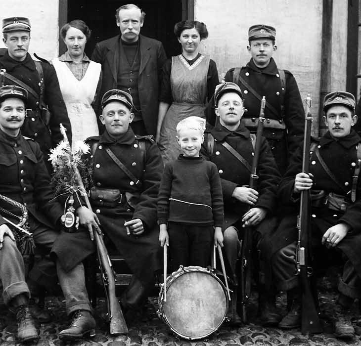 Eine Gruppe von Soldaten mit Gewehren und ein Junge mit einer Trommel