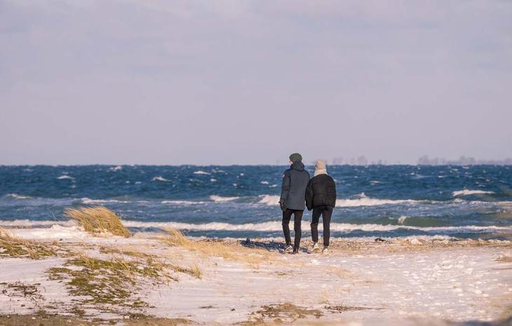 Ein Paar geht im Winter am Flyvesandet Strand spazieren